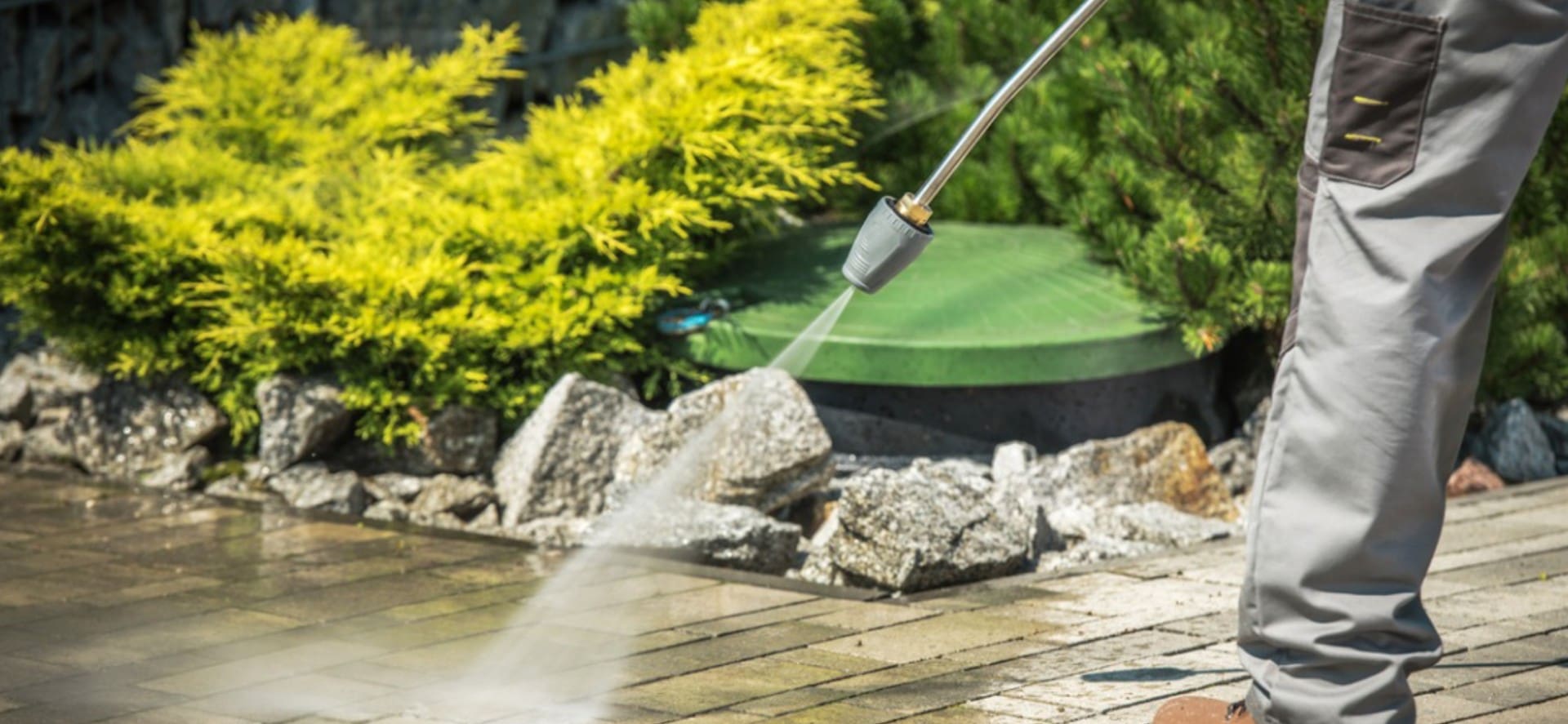 A person using a power washer on the ground.