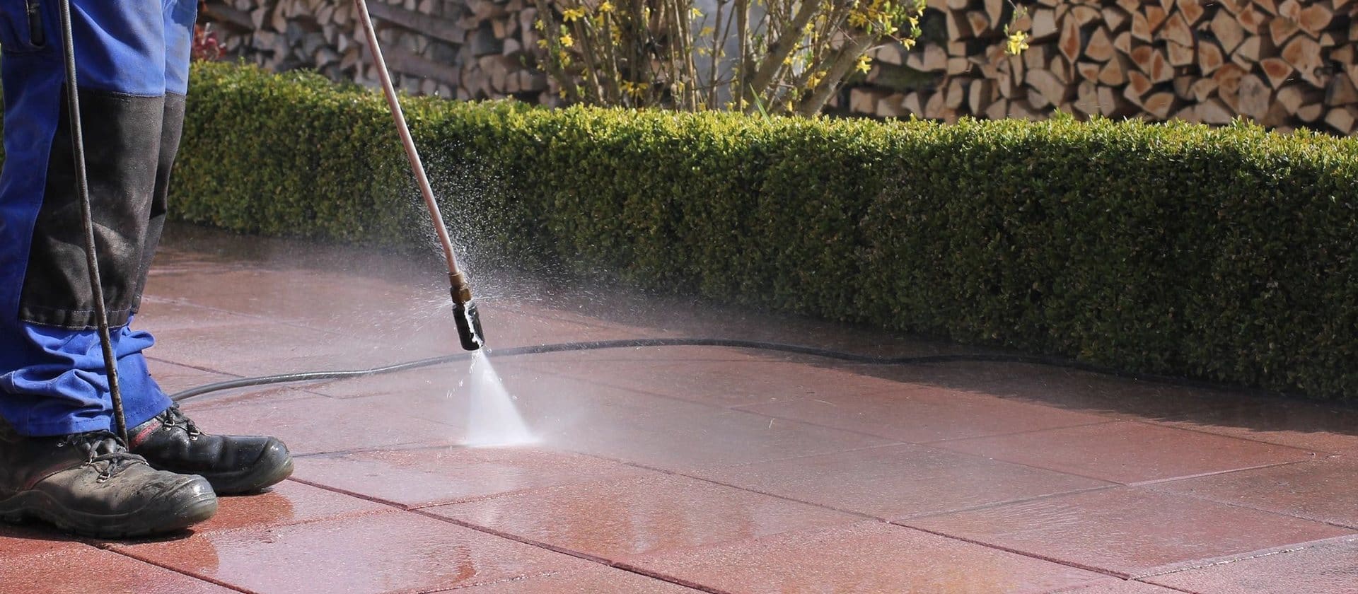 A person using a power washer on the ground.