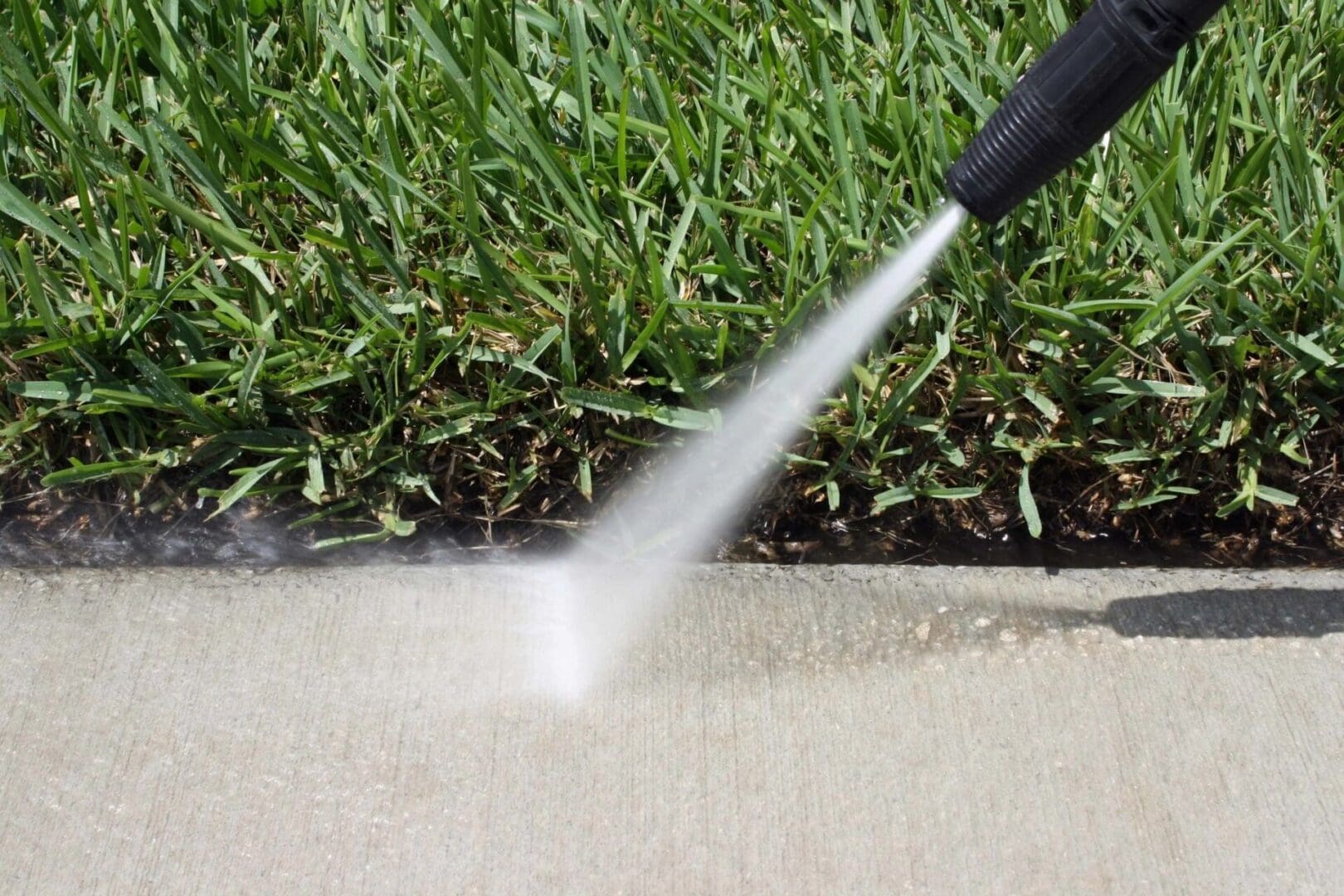 A person using a hose to clean the sidewalk.