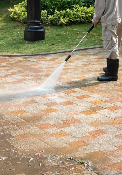 A person using a power washer on the ground.